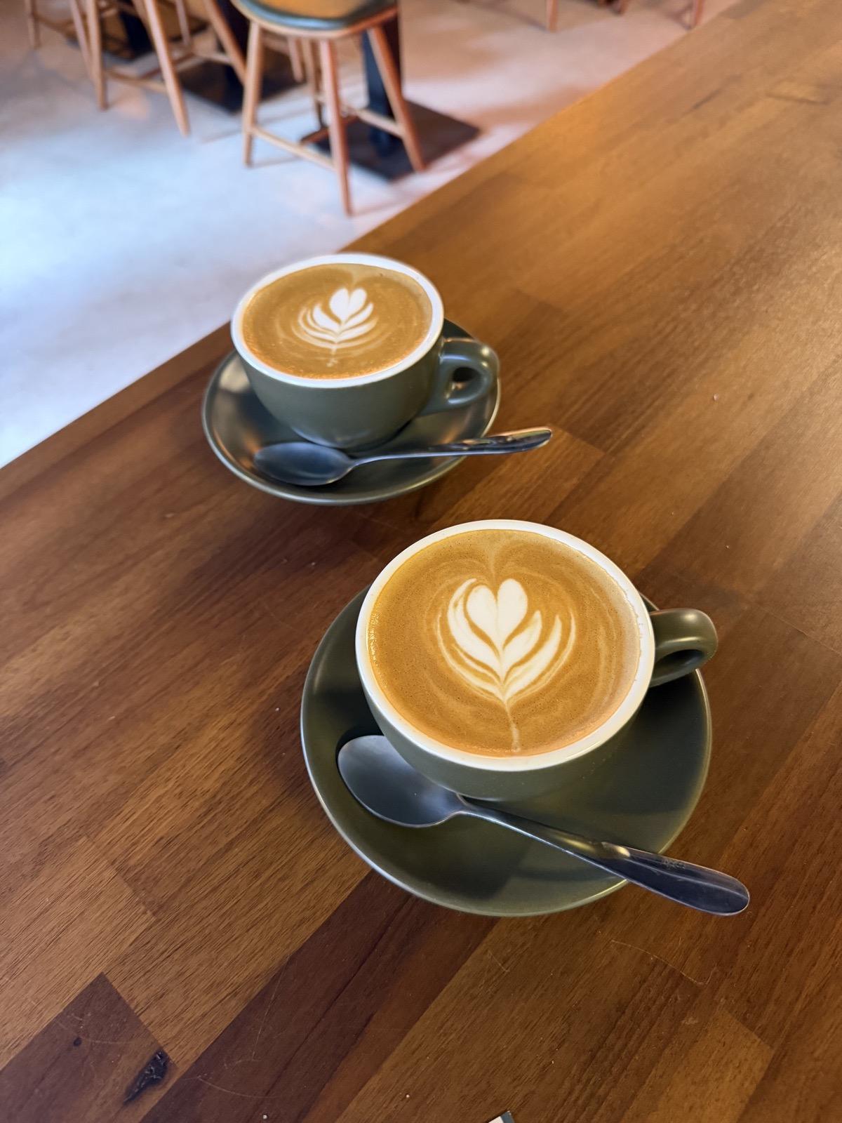 Two flat whites with latte art on a wooden counter