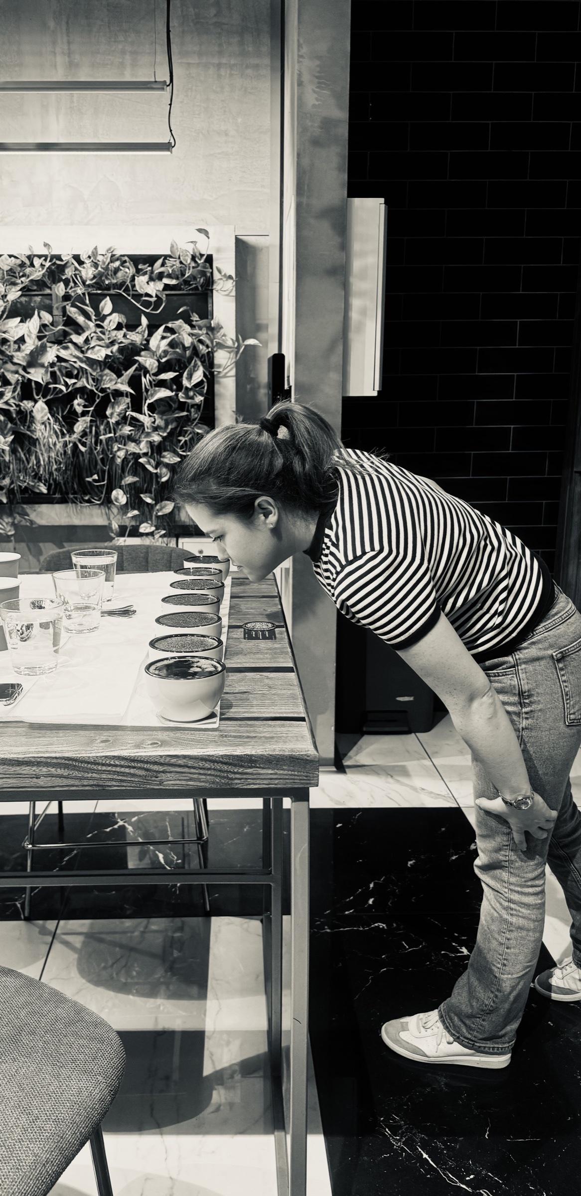 Erin leaning over a row of cupping bowls, smelling the coffee