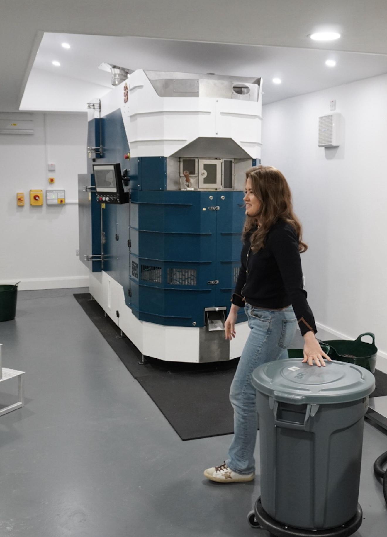 Erin beside the coffee roaster in the roastery